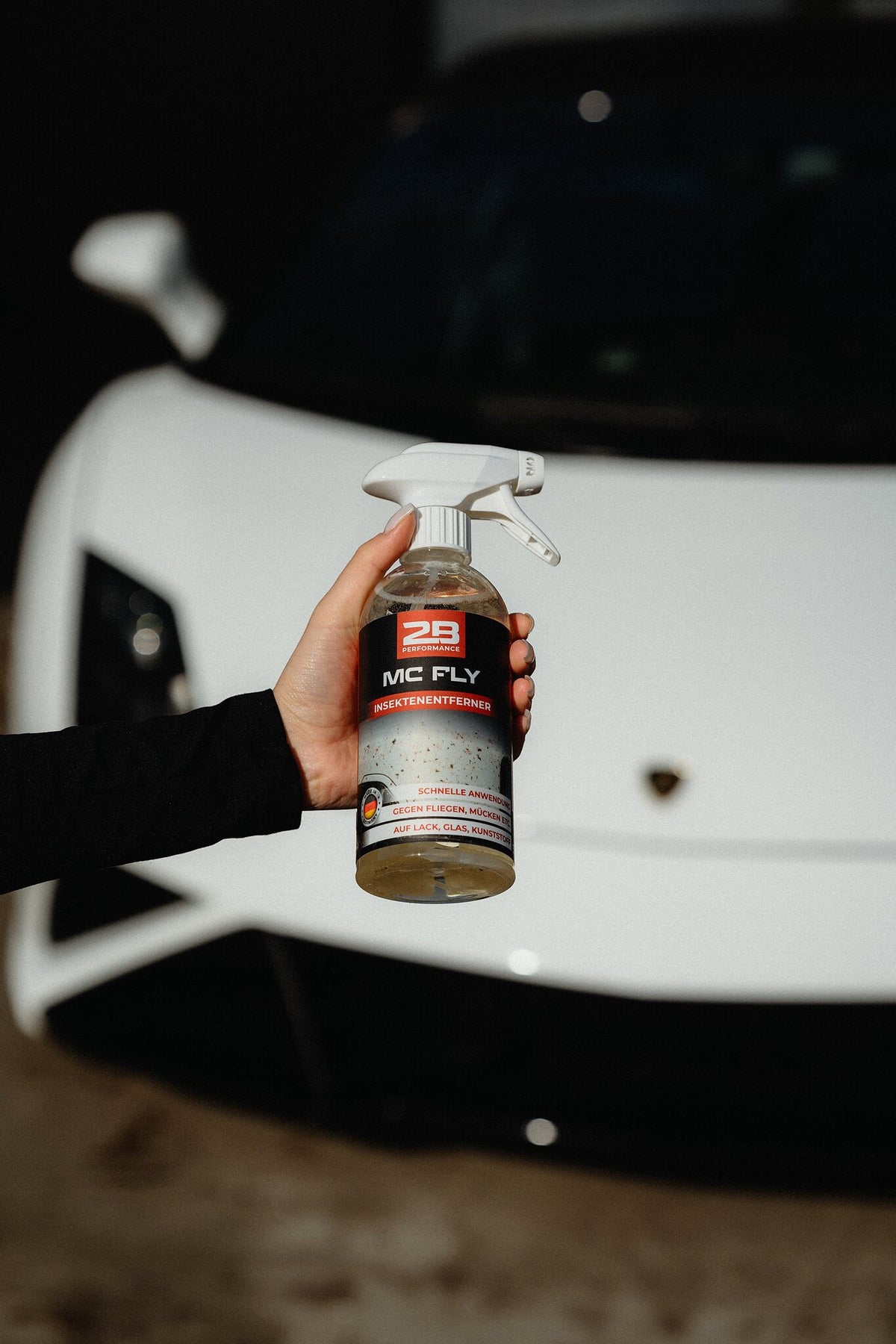 2B Performance Mc Fly Insektenentferner 500 ml – in der Hand vor einem Fahrzeug